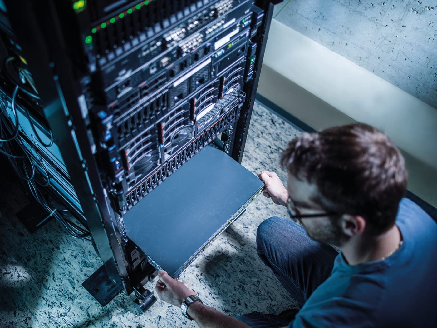 IT-Techniker arbeitet kniend an einem Server-Rack